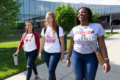 Three happy students walking side by side on a sunny day on the IUPUC campus.